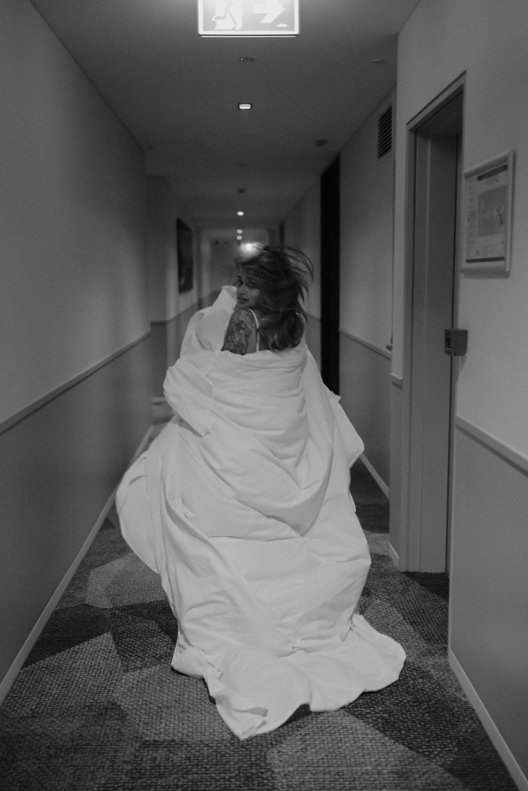 bride running through the hotel hallway in a white sheet